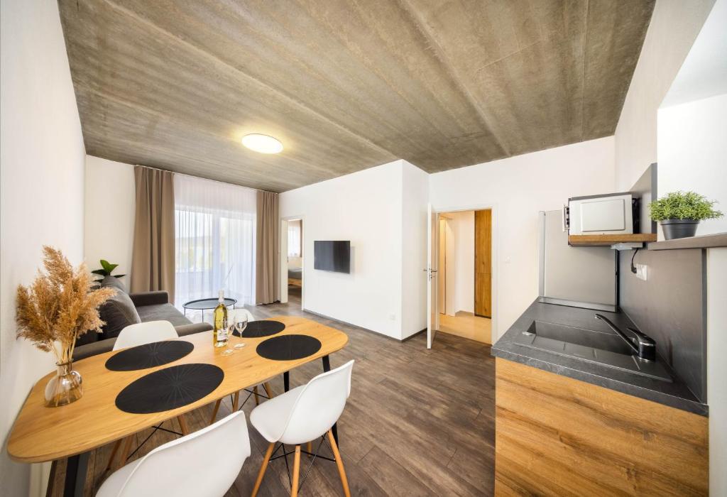a living room with a wooden table and white chairs at Apartmány Panelka Costa Plana Lipno in Černá v Pošumaví