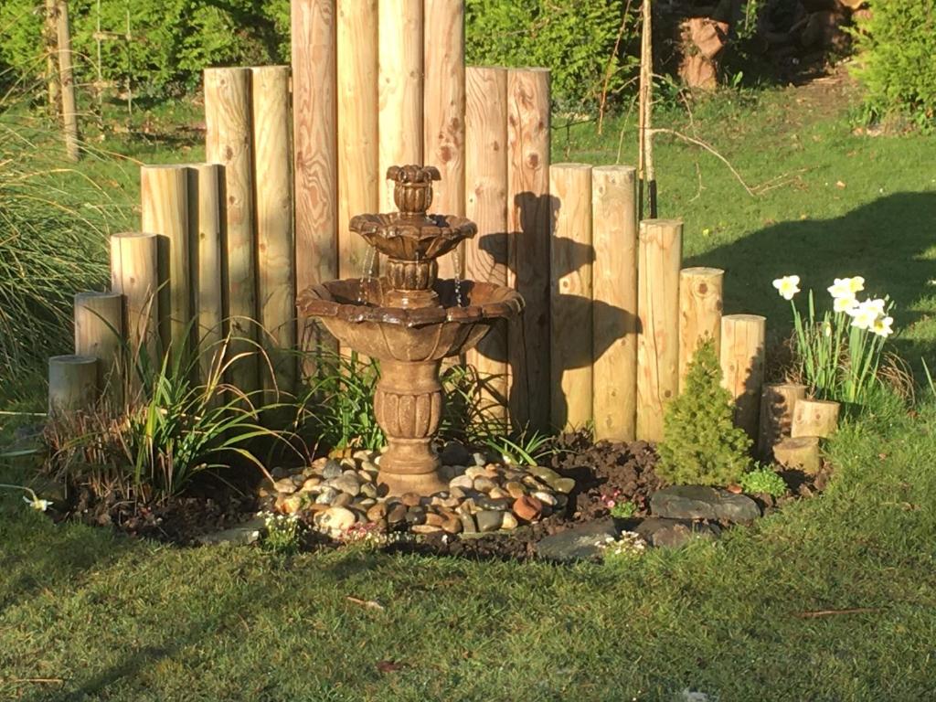a fountain in a garden in front of a fence at Willow House B&B in West Wittering