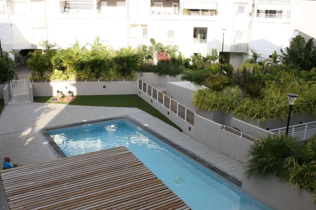 an apartment patio with a swimming pool and plants at à deux pas du lagon bel appartement quartier très vivant à l'hermitage in Saint-Gilles les Bains