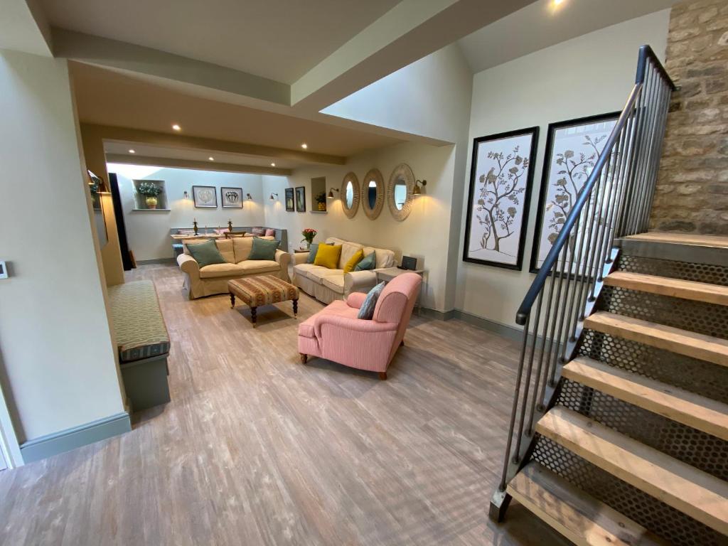 a living room with couches and a staircase at Rectory Farm Barn in Grantham