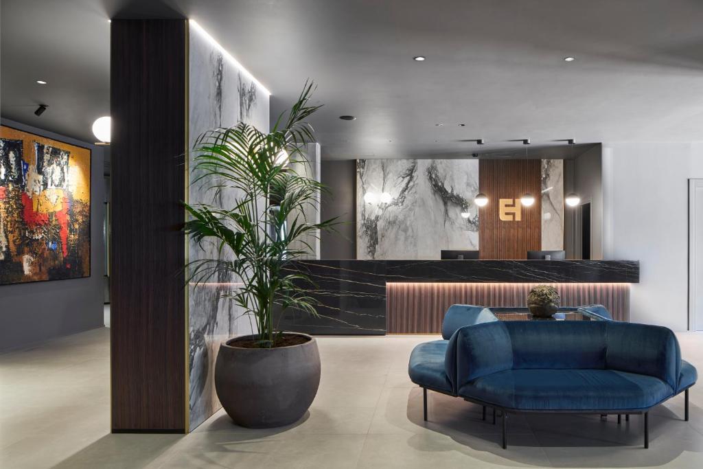 um hall de entrada com um sofá azul e uma planta em vasos em Executive Spa Hotel em Fiorano Modenese