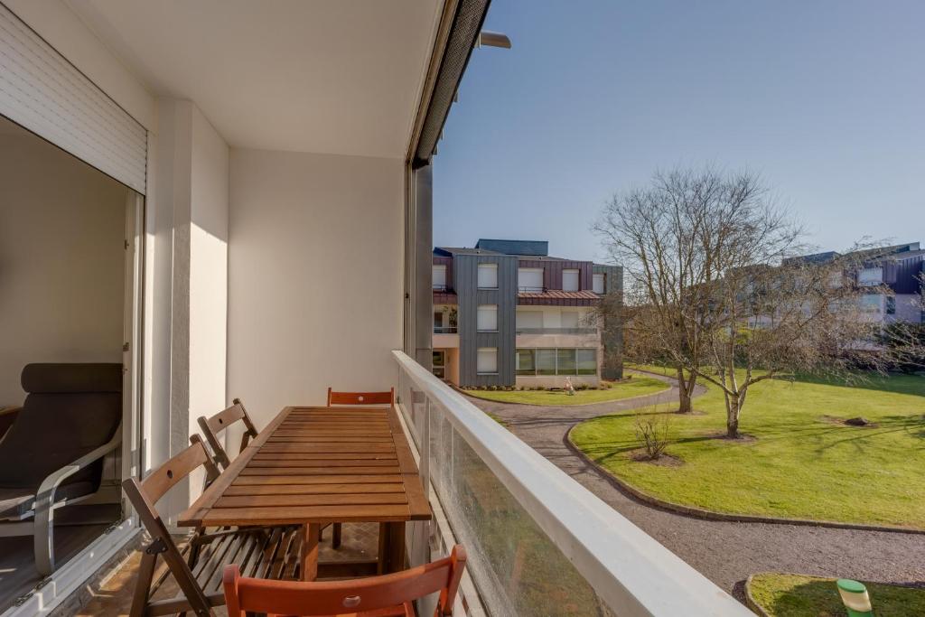 d'un balcon avec une table en bois et une vue sur un bâtiment. dans l'établissement Tribord, à Courseulles-sur-Mer