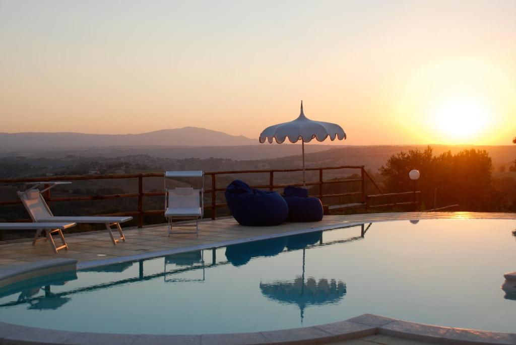 a swimming pool with a sunset in the background at Tenuta San Savino delle Rocchette in Poggiolo