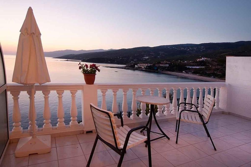 a balcony with two chairs and a table and an umbrella at kirki rooms in Armenistis