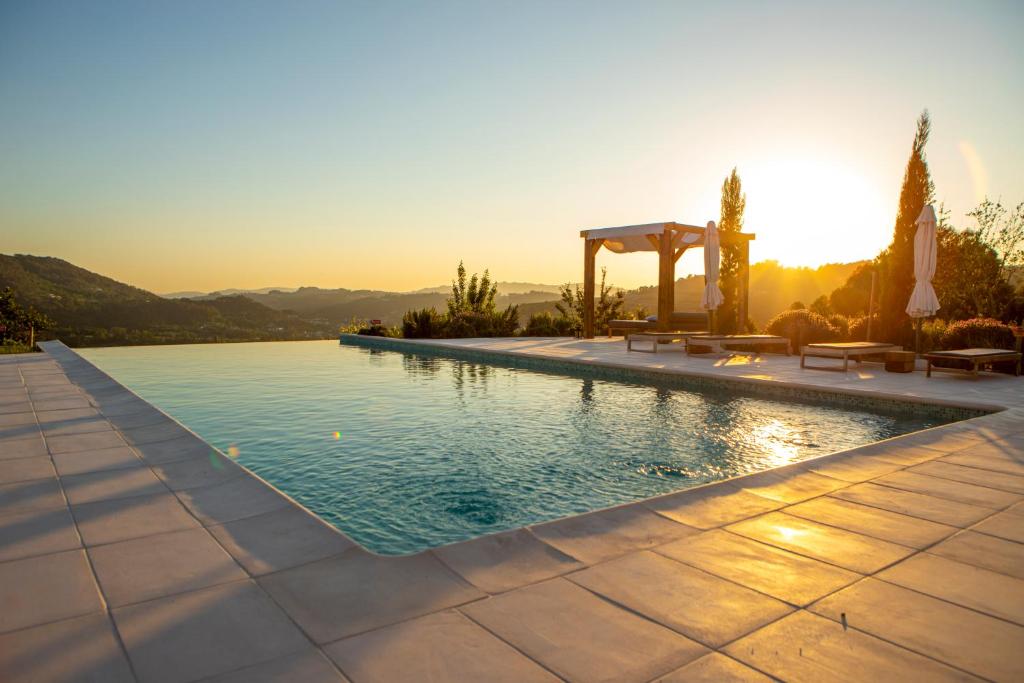 a swimming pool with a gazebo and the sunset at Peso Village in Amarante