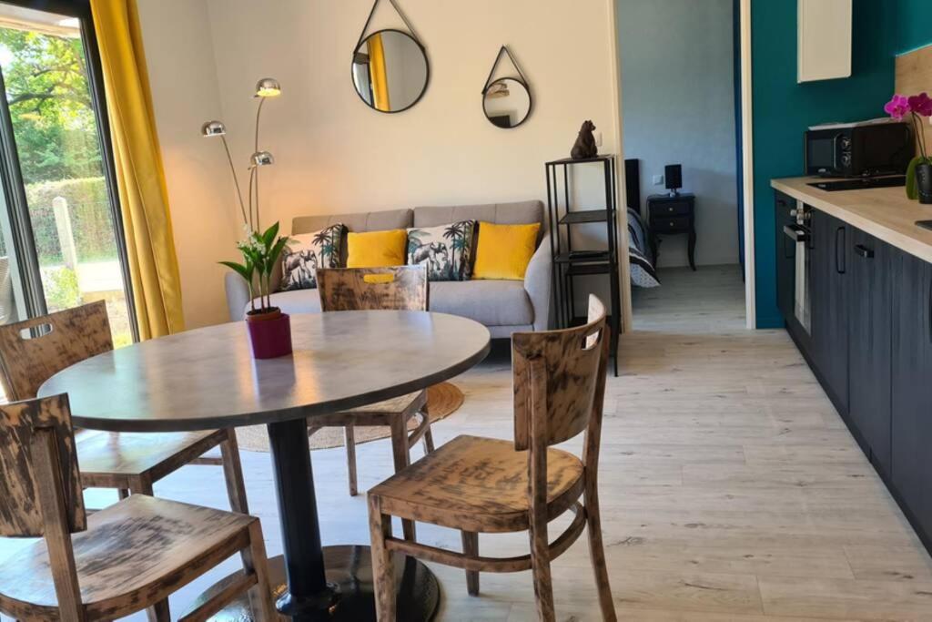 ein Wohnzimmer mit einem Tisch, Stühlen und einem Sofa in der Unterkunft Maison en bois presqu’île de rhuys Morbihan in Le Tour-du-Parc