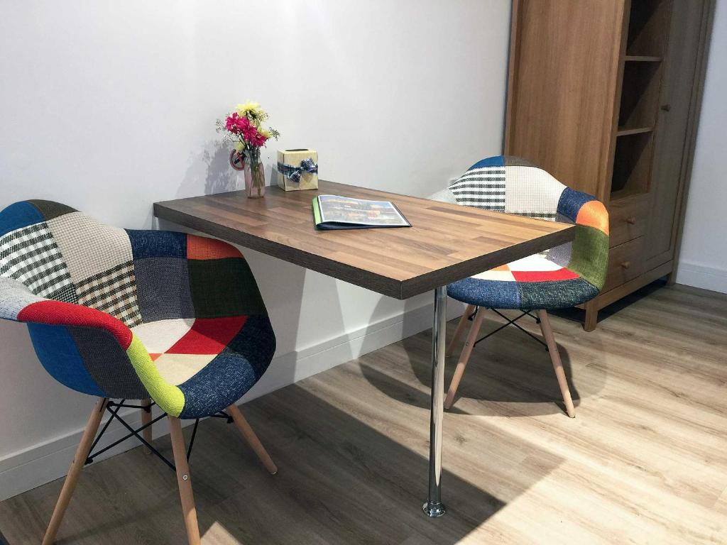 uma mesa de madeira com duas cadeiras num quarto em Beaverhall Apartments em Edimburgo
