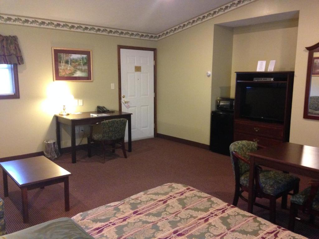 a hotel room with a bed and a desk and a television at Fred's Inn Restaurant & Lodging in Norwich