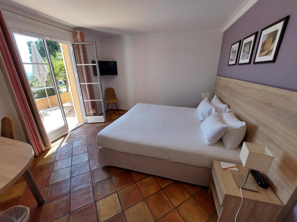 a bedroom with a large white bed and a window at Hôtel les Bouis - Vue mer in Saint-Tropez