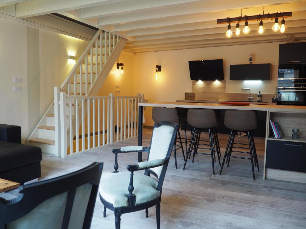 a living room with a bar with chairs and a staircase at La Meïzou de Bouly in Martres-de-Veyre