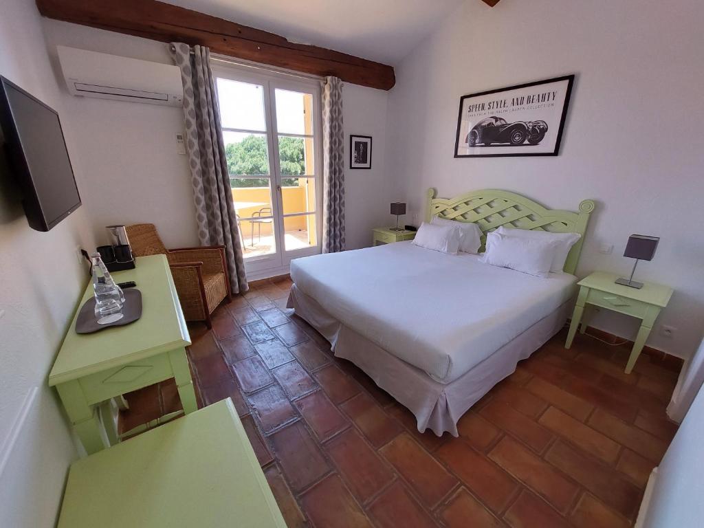 a bedroom with a white bed and a window at Hôtel les Bouis - Vue mer in Saint-Tropez