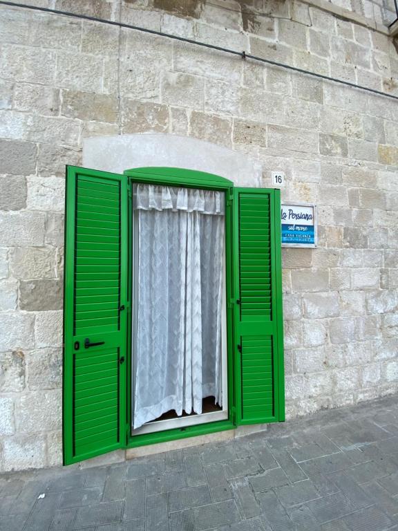 a window with green shutters on a brick building at La persiana sul mare in Giovinazzo