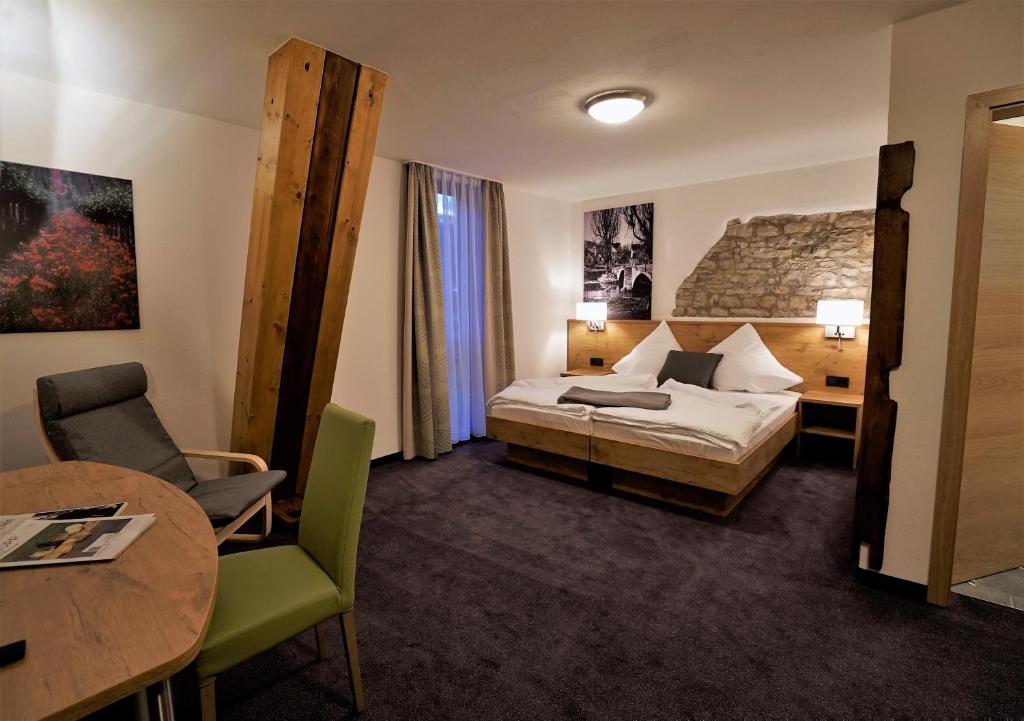 ein Hotelzimmer mit einem Bett und einem Tisch in der Unterkunft Kelterhotel Fröscher in Forchtenberg