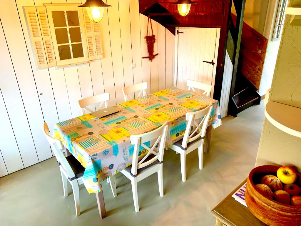 a dining room table with white chairs and a table and a bowl of fruit at Ysermonde Fisherman's Cottage in Nieuwpoort