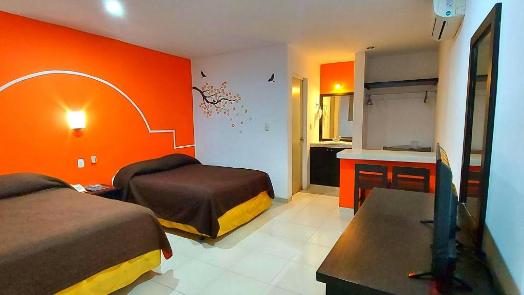 a bedroom with two beds and an orange wall at Hotel El Marques in Mérida