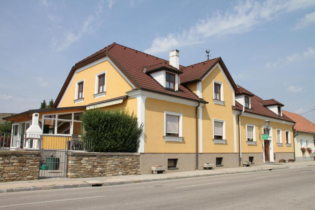 uma casa amarela ao lado de uma rua em Gästehaus Fischer Rohrendorf em Rohrendorf bei Krems