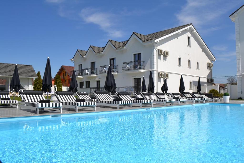 ein Hotel mit einem Pool mit Stühlen und Sonnenschirmen in der Unterkunft Krystal Boutique Mansion in Hunedoara