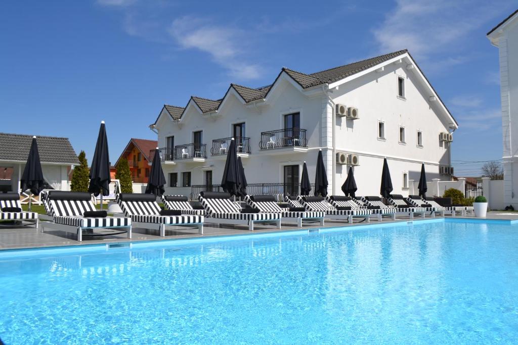 um hotel com uma piscina com cadeiras e guarda-sóis em Krystal Boutique Mansion em Hunedoara