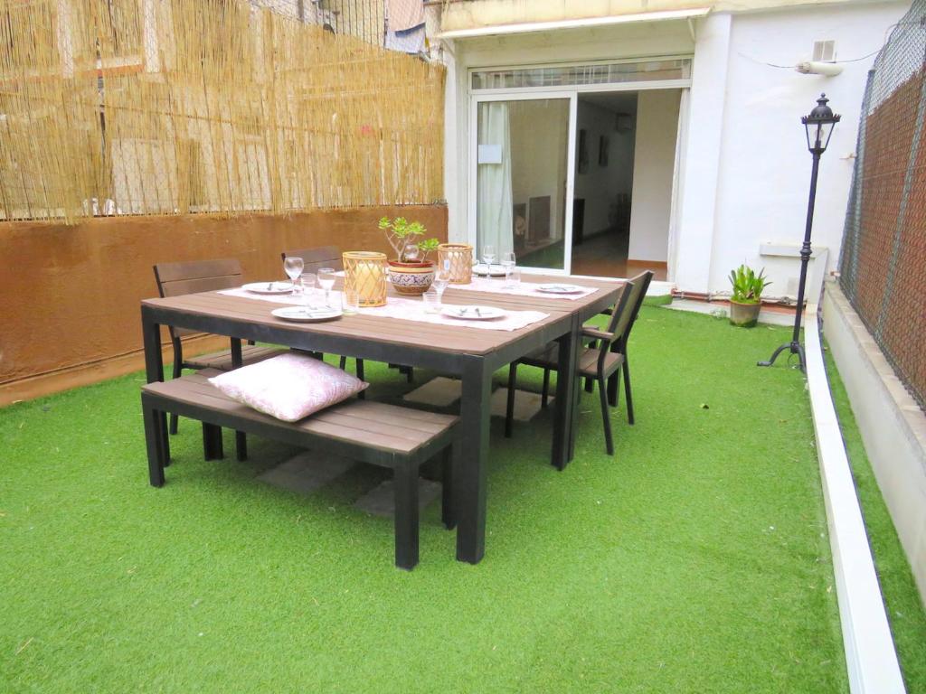una mesa y sillas en un patio con césped verde en Stay U-nique Apartments Urgell, en Barcelona