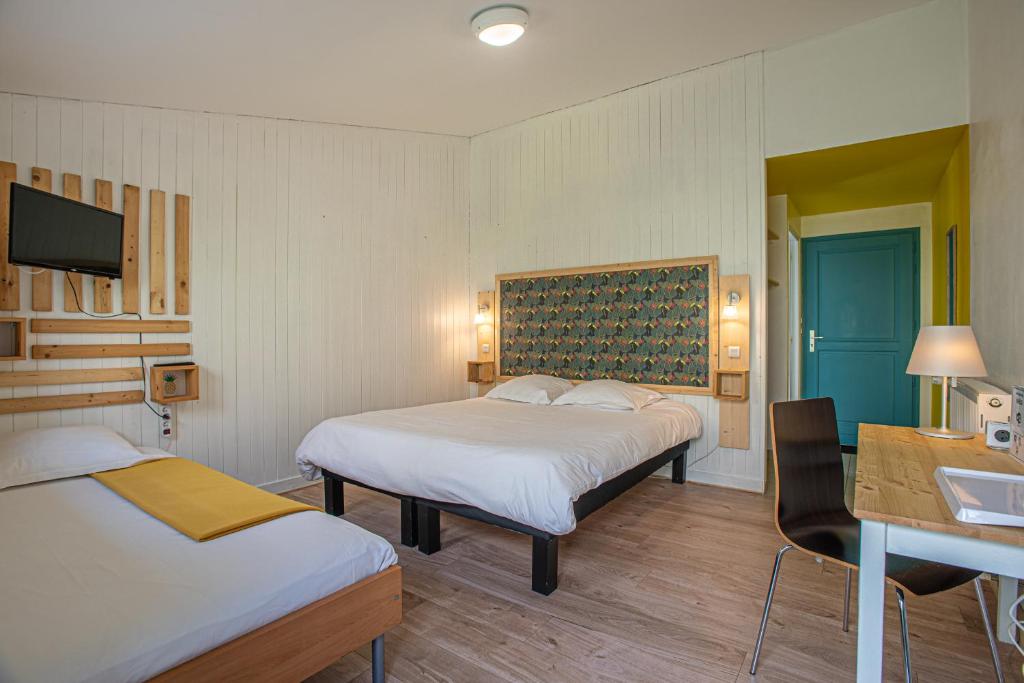 オーディエルヌにあるHôtel Naéco Audierneのベッド2台、デスク、テレビが備わるホテルルームです。