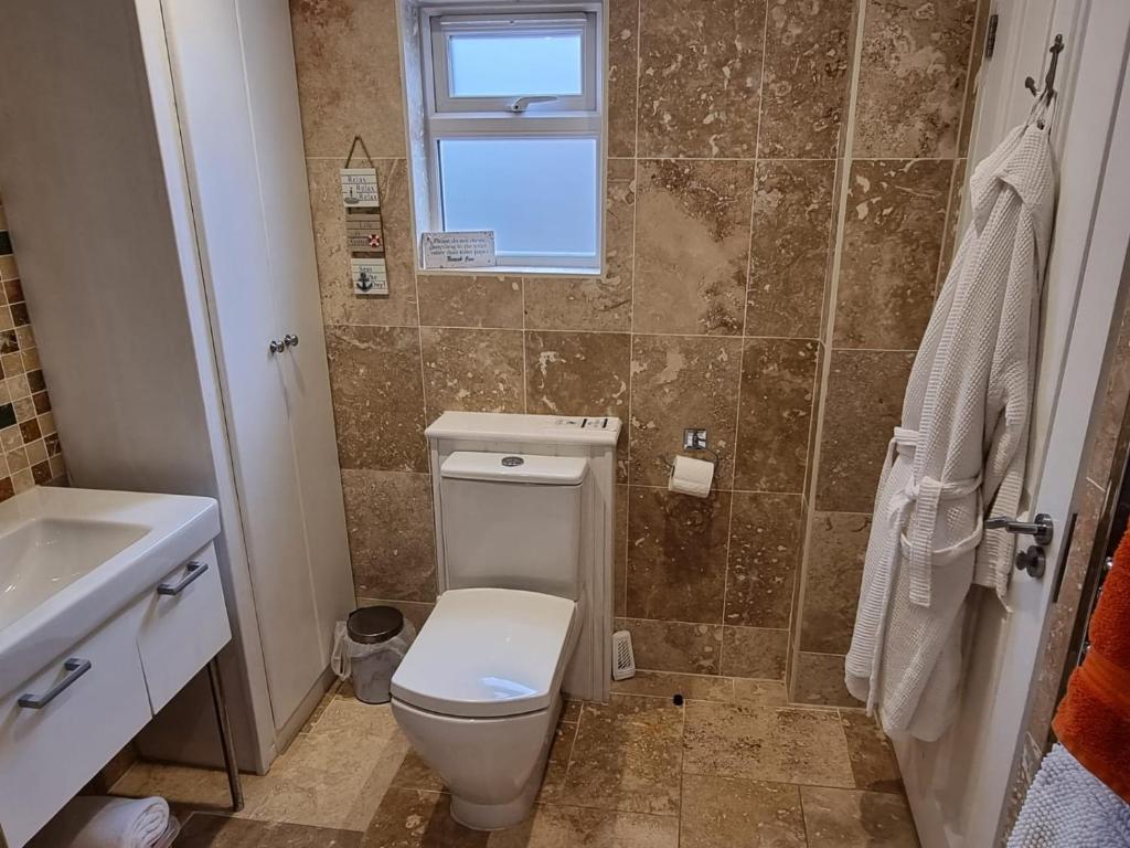 a bathroom with a toilet and a sink and a window at Willow House B&B in West Wittering