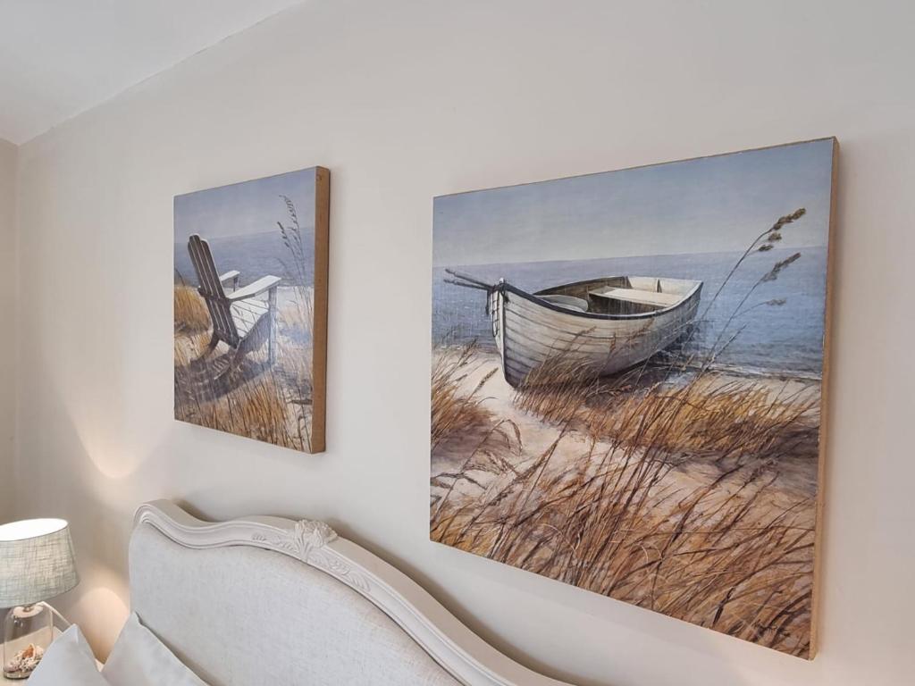 two paintings of a boat on a beach at Willow House B&B in West Wittering