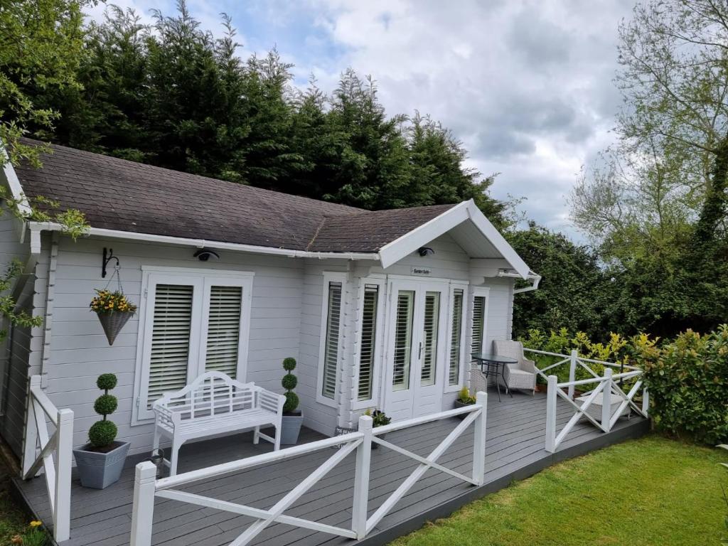 a white cabin with a bench on a deck at Willow House B&B in West Wittering
