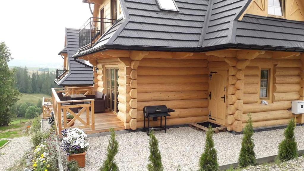 drewniany domek z czarnym dachem i stołkiem na zewnątrz w obiekcie Domek z bali w Murzasichlu