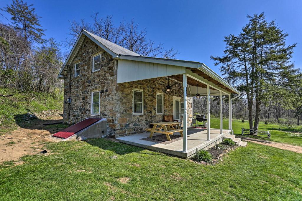 a stone house with a picnic table in the yard at Idyllic Hellertown Cottage with Patio and Fire Pit! in Bethlehem