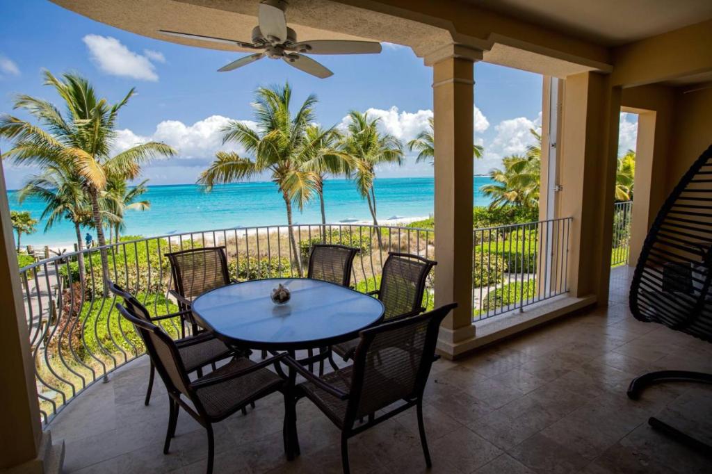 una mesa y sillas en un balcón con vistas al océano en Villa Renaissance Unit 205 Grace Bay Beach en Grace Bay
