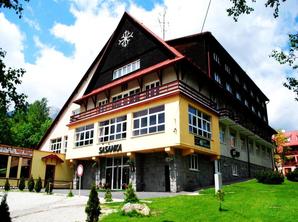 un grand bâtiment avec un toit en gambrel dans l'établissement Hotel Sasanka, à Tatranská Lomnica