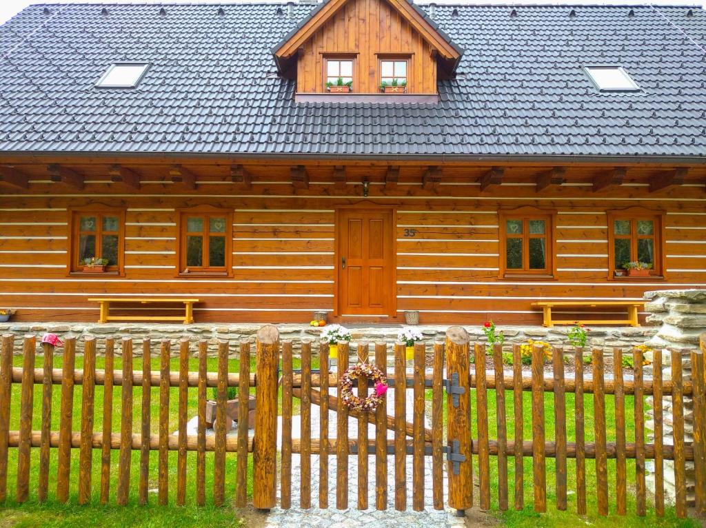 a wooden house with a fence in front of it at Apartmány u vlčích jam in Petrovice u Susice