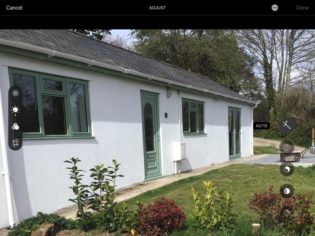 ein weißes Haus mit grünen Fenstern und einem Hof in der Unterkunft Sycamore Bungalow in Perranwell