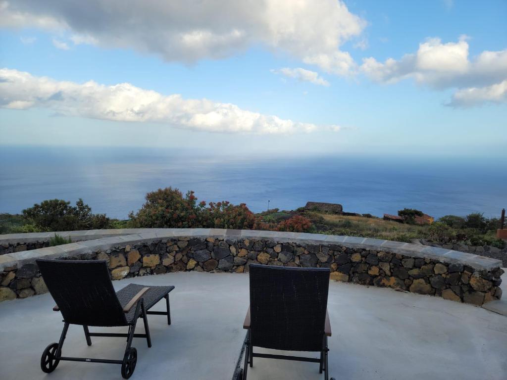 two chairs and a table on a patio overlooking the water at Sitio la era in Fuencaliente de la Palma