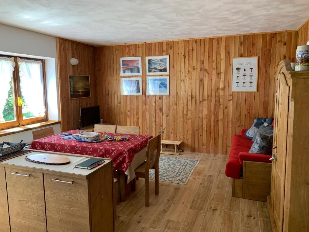 ein Esszimmer mit einem Tisch und einem roten Sofa in der Unterkunft Appartamento Tapì in Passo del Tonale