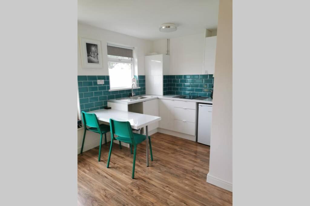 a kitchen with a table and green chairs at Stylish studio bungalow, close to Cardiff Centre in Cardiff