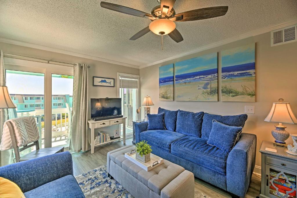 a living room with a blue couch and a tv at Soothing Oceanview Condo with Direct Beach Access! in Atlantic Beach