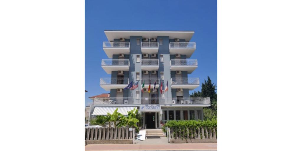 een hoog blauw gebouw met vlaggen ervoor bij Hotel President in San Benedetto del Tronto