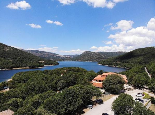 Blick auf einen See mit einem Haus und Bäumen in der Unterkunft Hotel Taloro in Gavoi