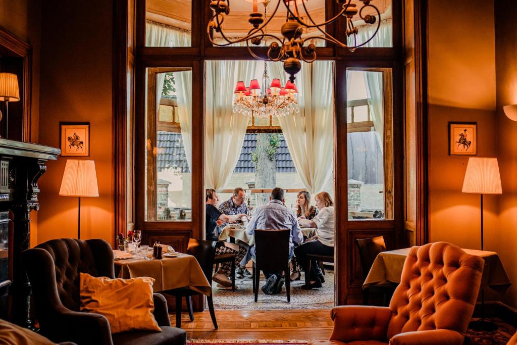 een groep mensen die aan tafel zitten in een restaurant bij B&B 't Kasteel & 't Koetshuys in Veurne