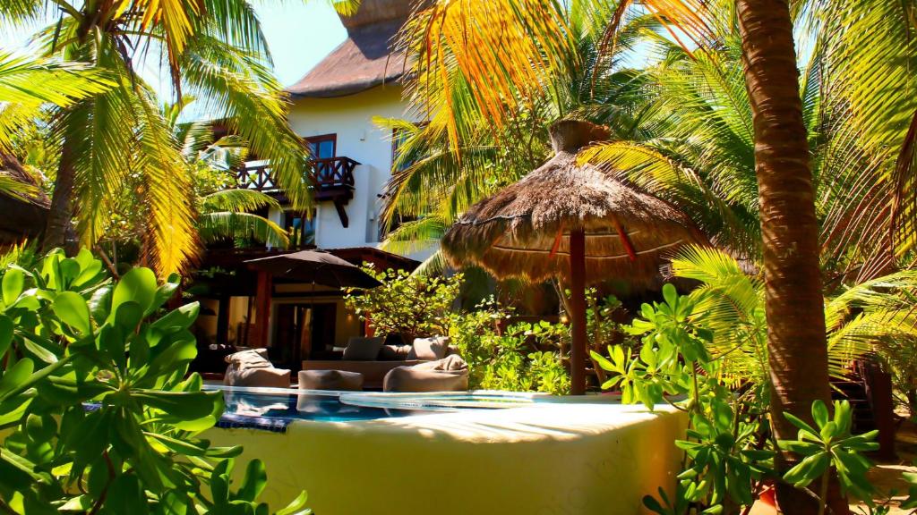 Uaymitun的住宿－Delos Luxury Villa，一个带遮阳伞和椅子的游泳池的度假酒店