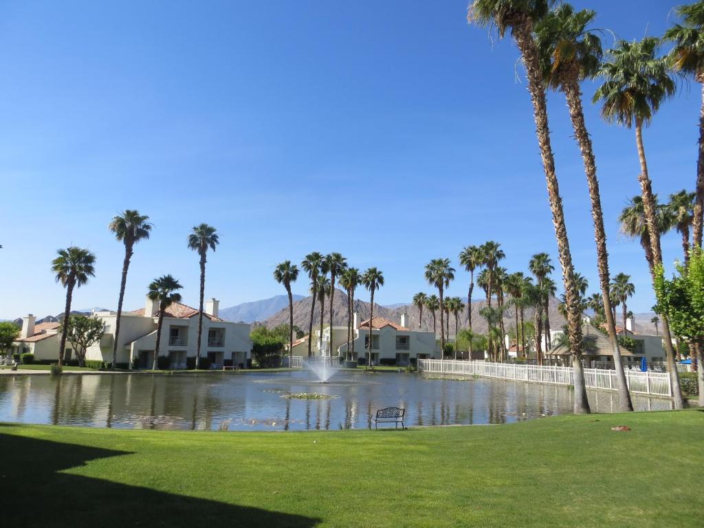 un parc avec des palmiers et un étang avec une fontaine dans l'établissement Desert Breezes Resort, à Palm Desert
