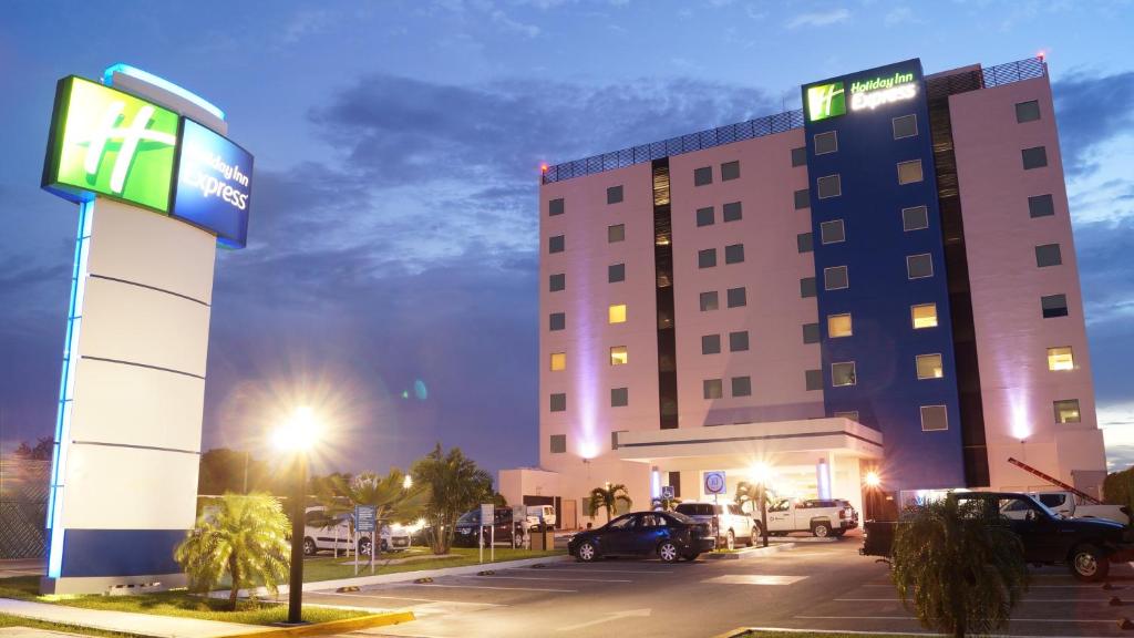 um edifício de hotel com um parque de estacionamento em frente em Holiday Inn Express Mérida, an IHG Hotel em Mérida