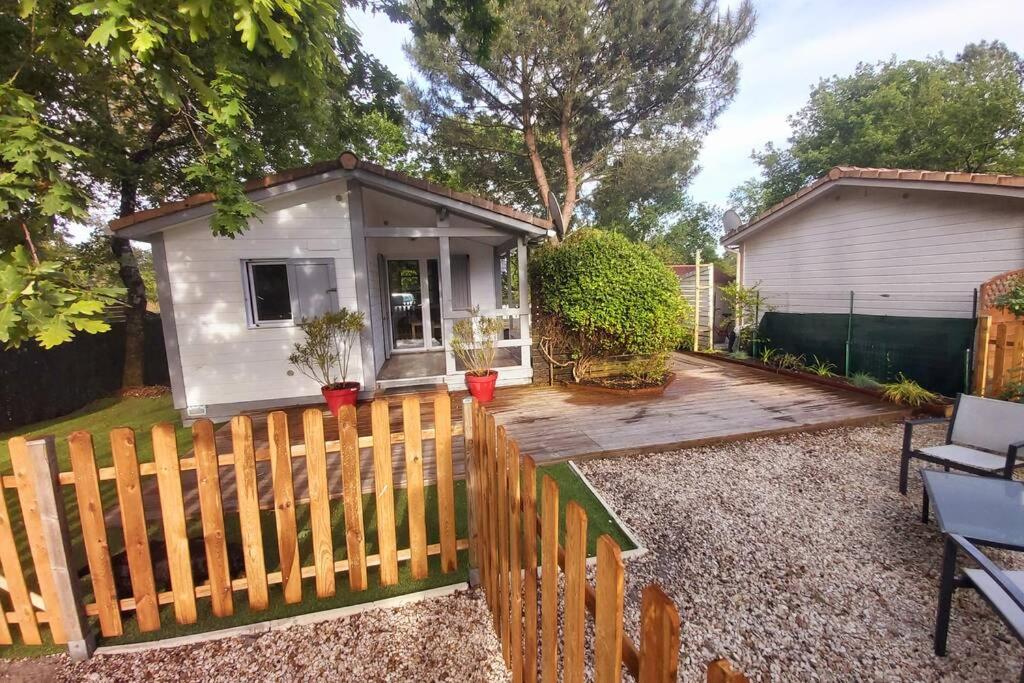 a tiny house in a backyard with a wooden fence at Chalet T3/clim/wifi/pkg/terrasse/15 min plages in La Teste-de-Buch