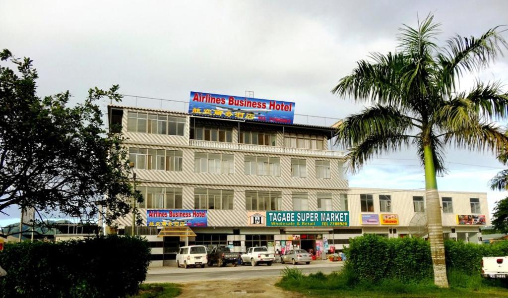 um edifício com uma palmeira em frente em Airlines Business Hotel em Port Vila