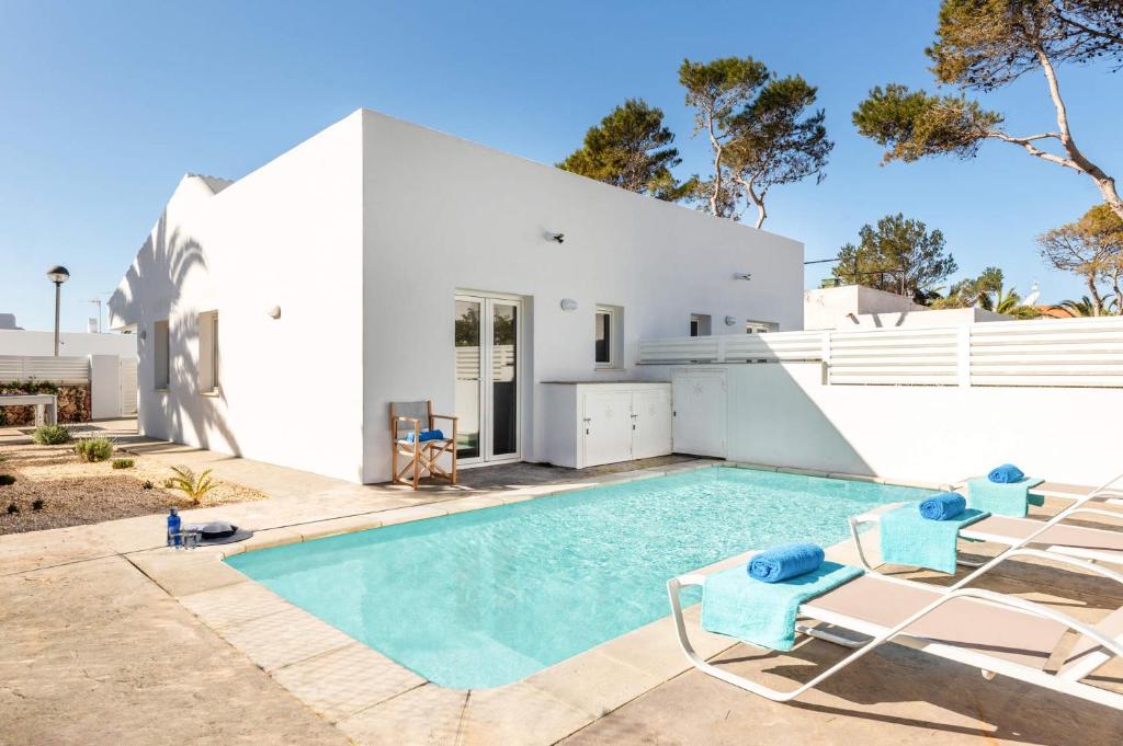 a white house with a swimming pool and chairs at Villa Pins Ciutadella by Villa Plus in Cala Blanca