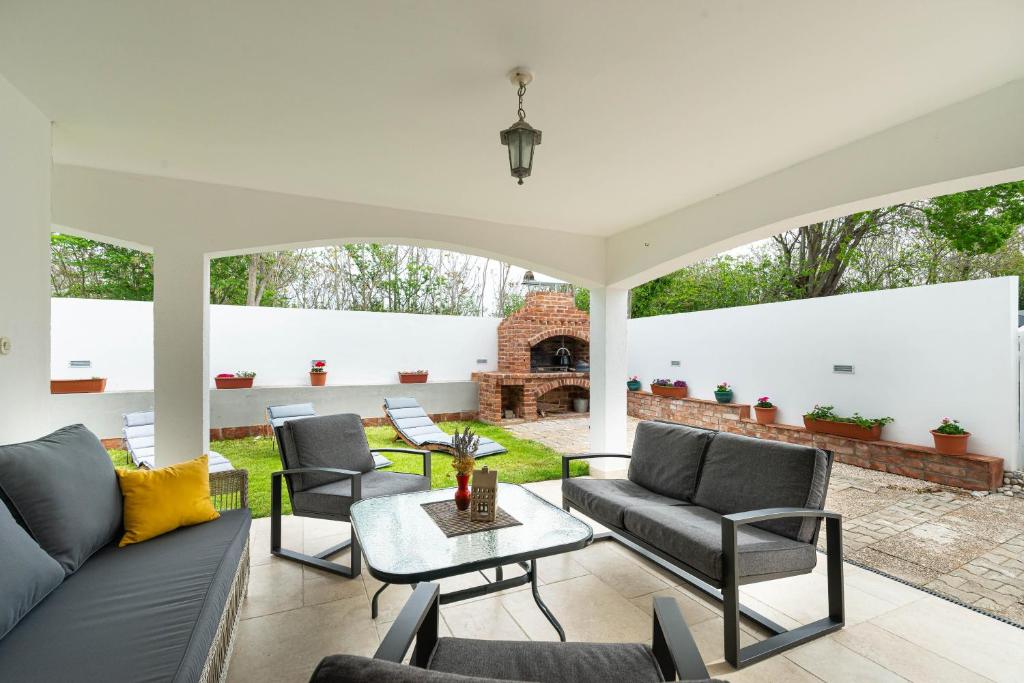 een patio met een bank en stoelen en een open haard bij Privlaka Holiday House in Privlaka