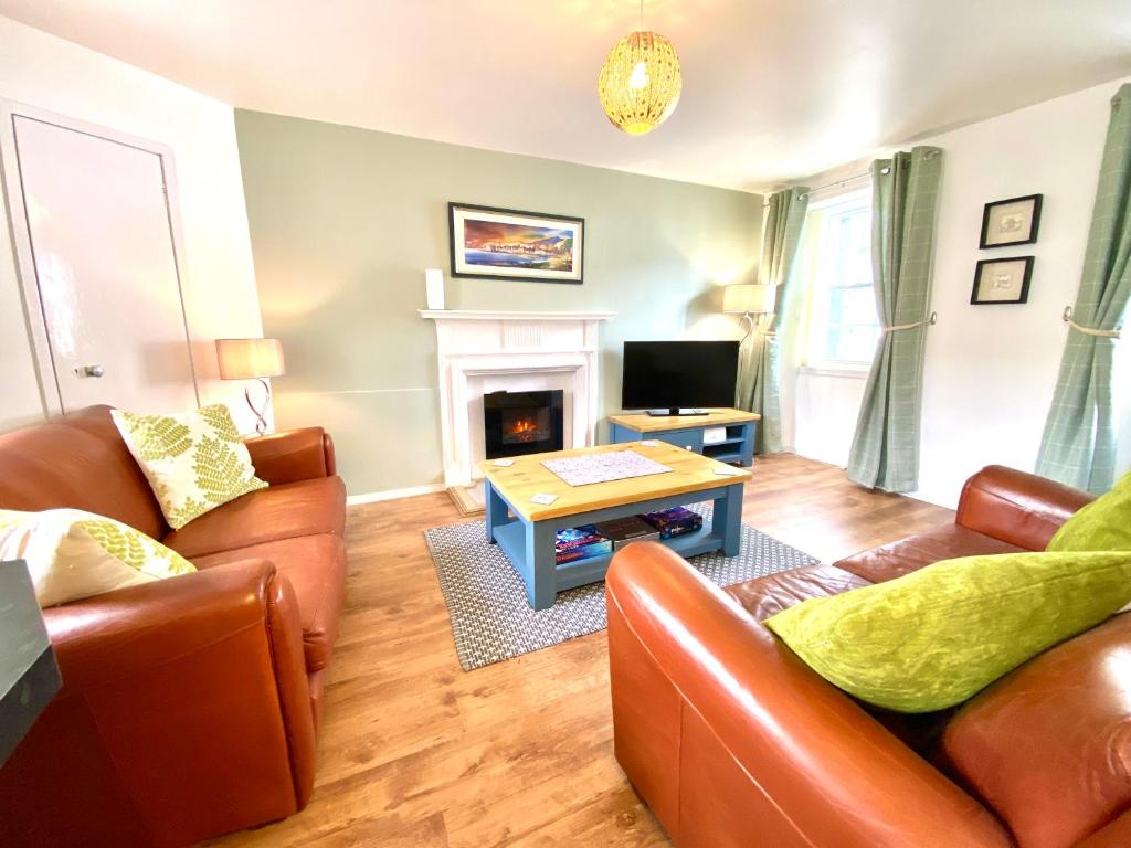 een woonkamer met lederen meubels en een open haard bij Cosy, Modern 2 Bedroom Apartment in the Centre of Inveraray in Inveraray