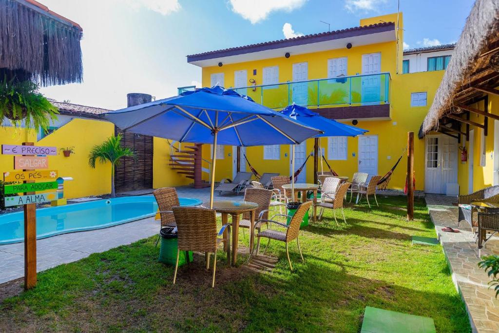 a table and chairs with umbrellas next to a pool at Pousada Summer Beach by AFT in Porto De Galinhas