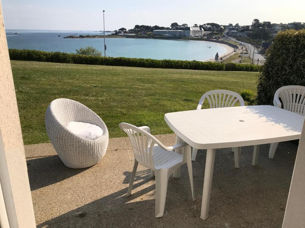 einen weißen Tisch und Stühle mit Meerblick in der Unterkunft COTTAGE vue sur mer piscine in Trévou-Tréguignec
